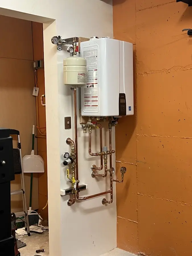Plumbing technician inspecting water heater connections in Cameron